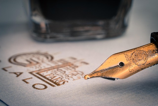 Dip pen beside an open ink bottle on a calligraphy workspace